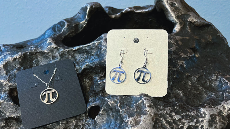 Silver-plated earrings and necklace depicting Pi . Both are resting on a meteorite.